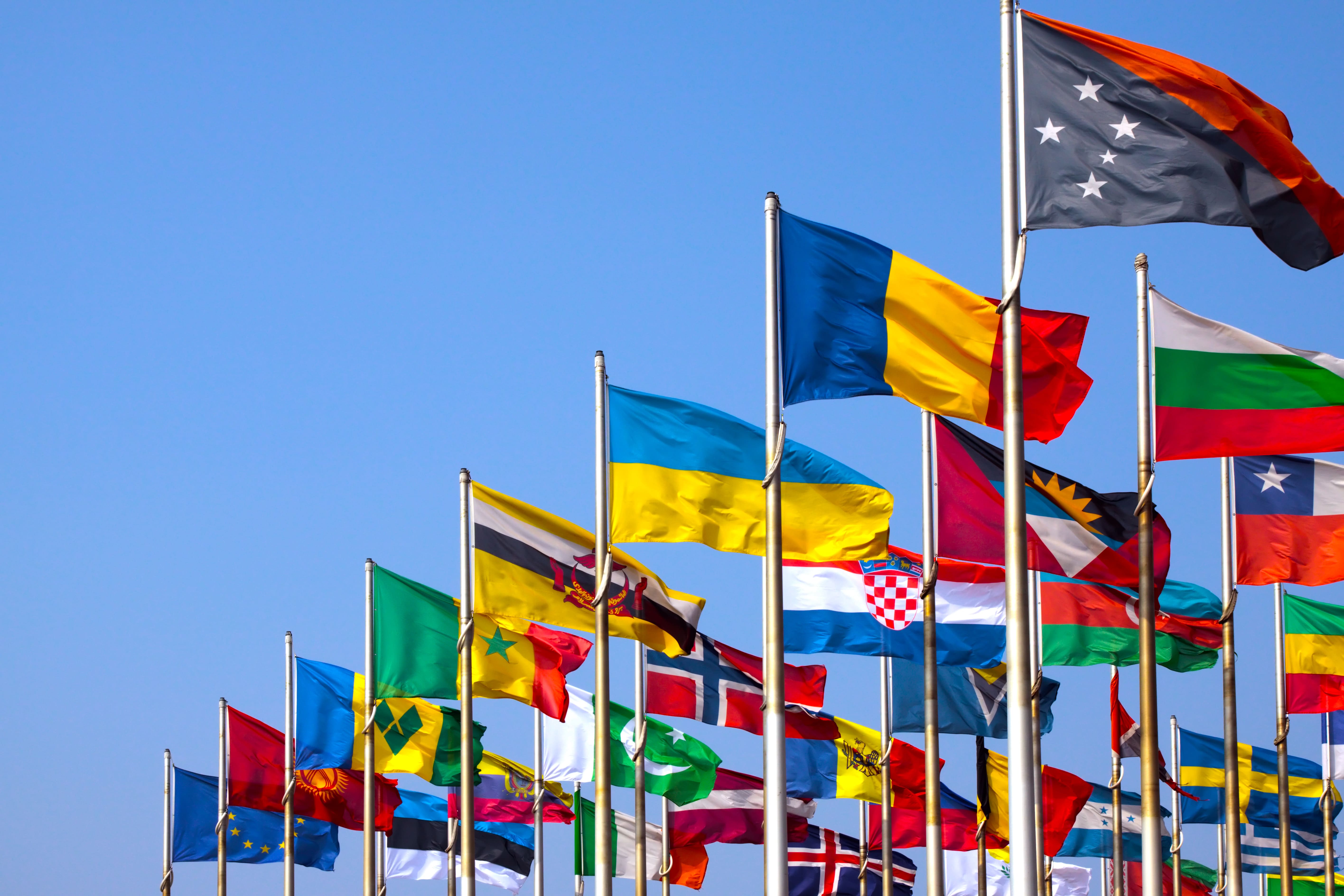 world flags flying in the wind in a clear blue sky