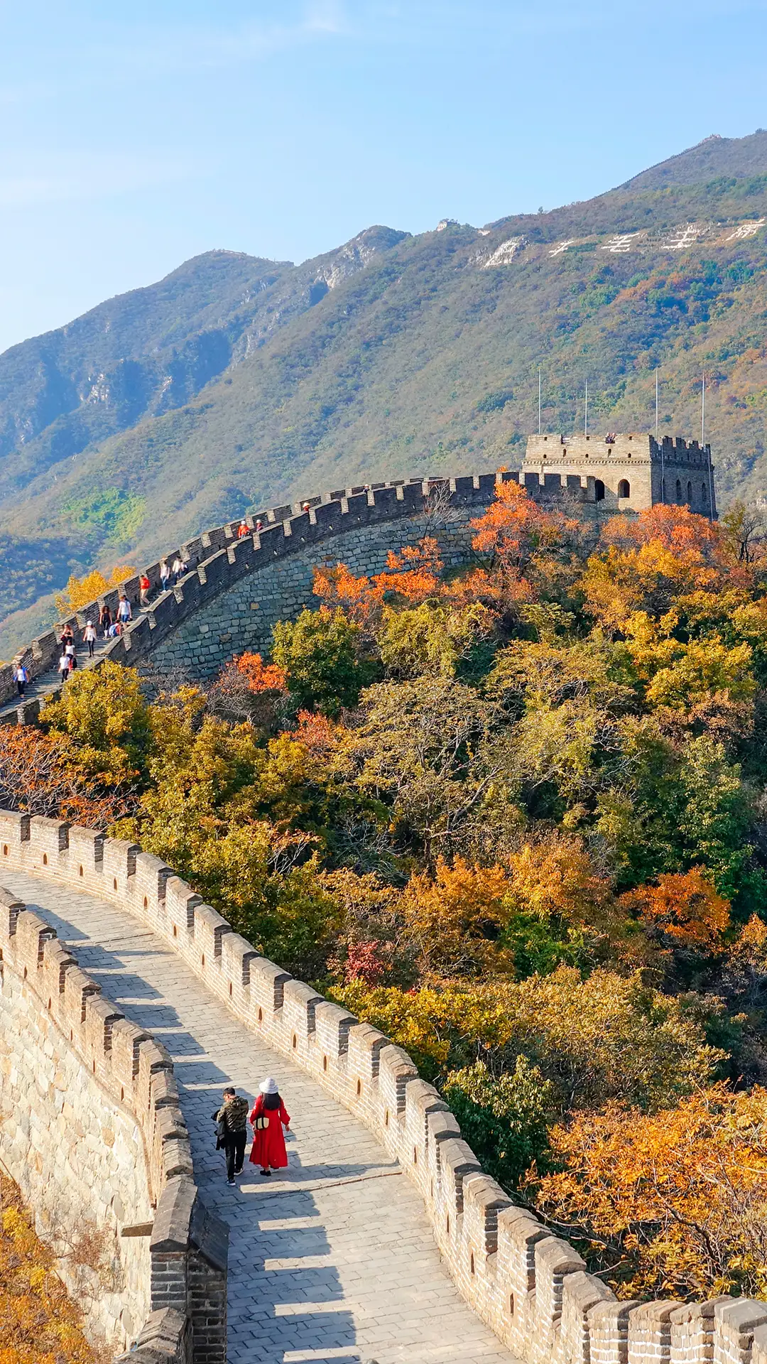 Two unrecognizable tourists walk along the walkway atop the Great Wall of China.