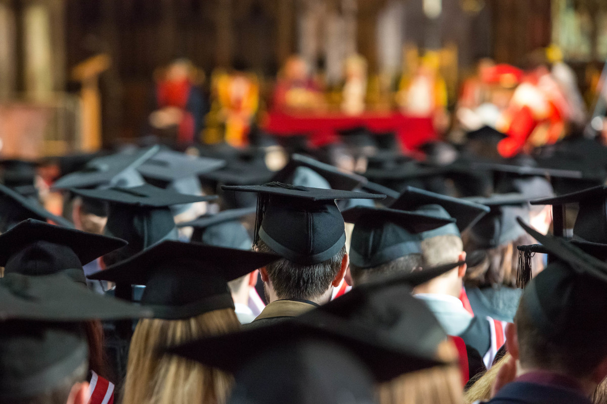 graduating students sitting in rows in Chester Cathedral at a graduation ceremony . View of the backs of their caps and gowns