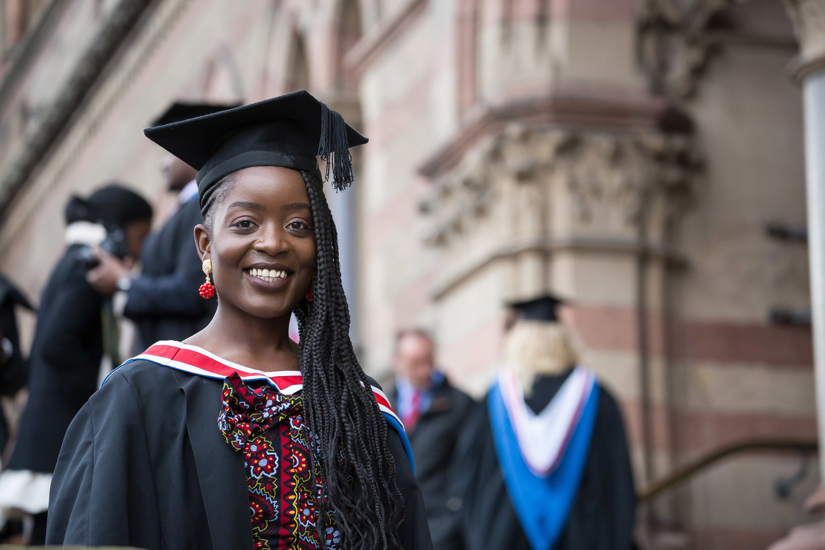 A female graduate in her cap and gown standing outside Chester Catherdral