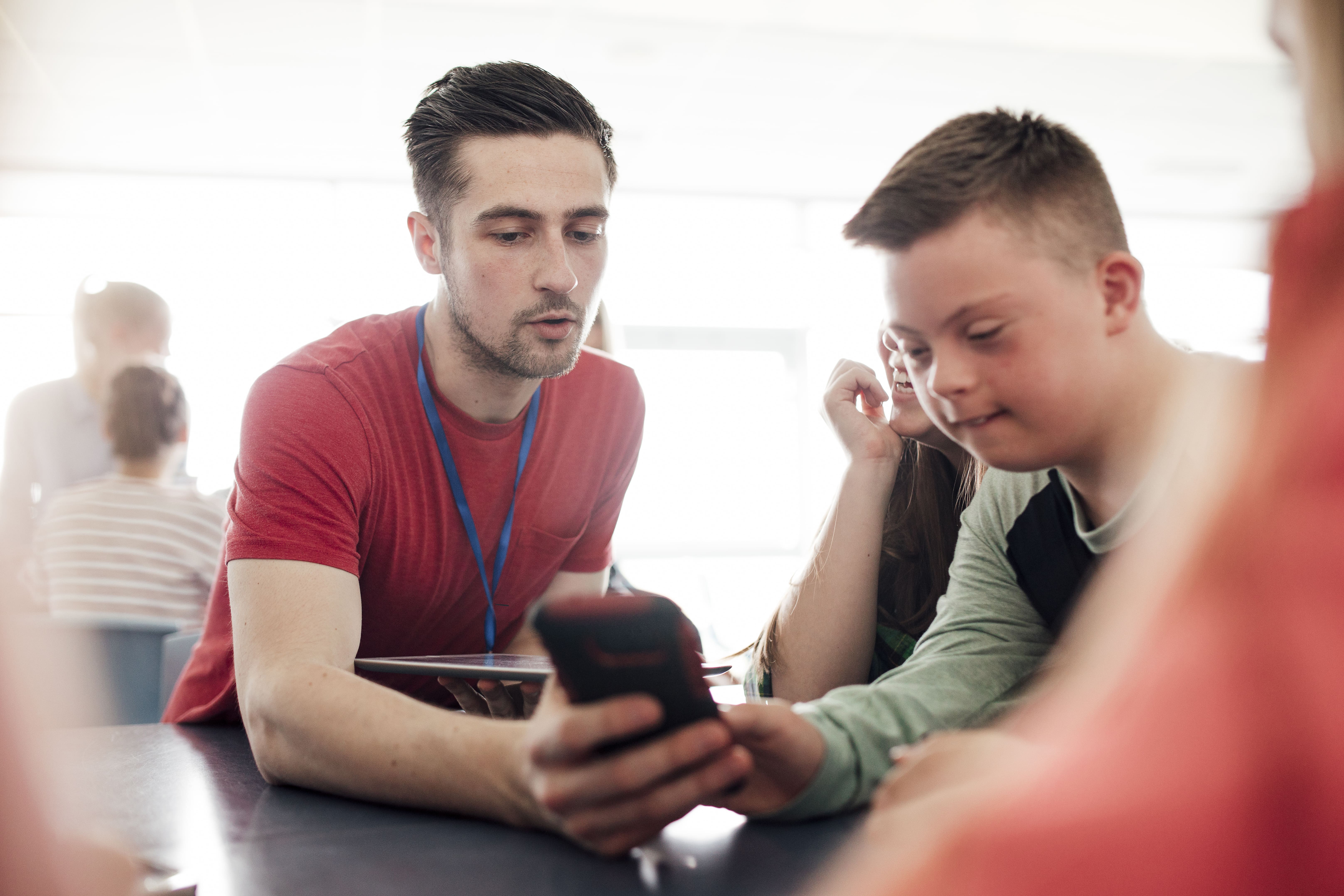 male teacher looking at a mobile phone with a boy with Down syndrome