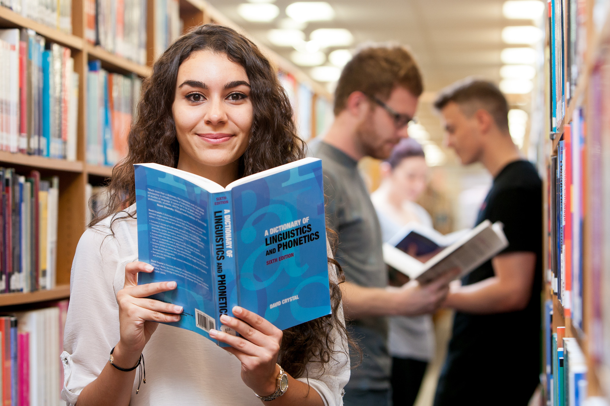 Student holding a book on linguistics and phonetics in Seaborne Library
