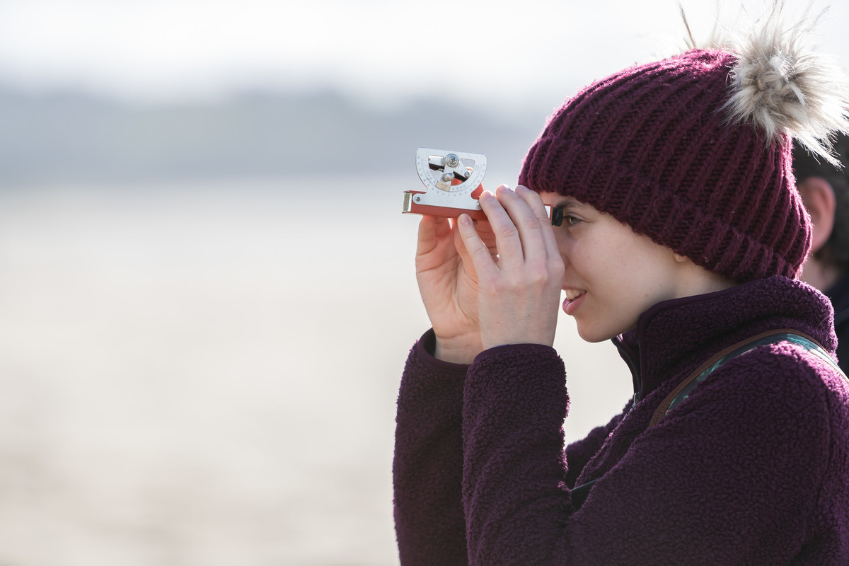 A student looking through binoculars at the distant landscape.