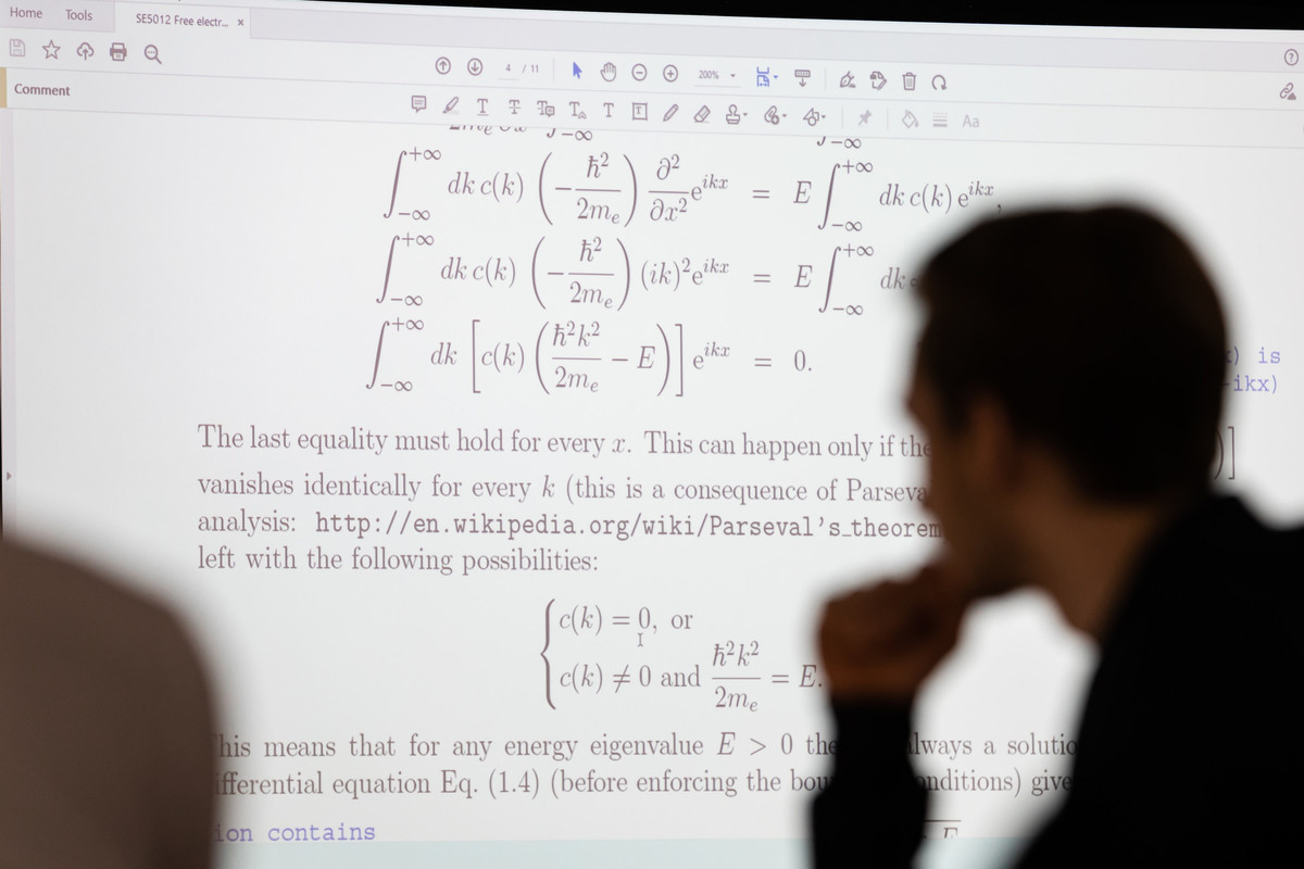 Students studying mathematics with wall screen in background.