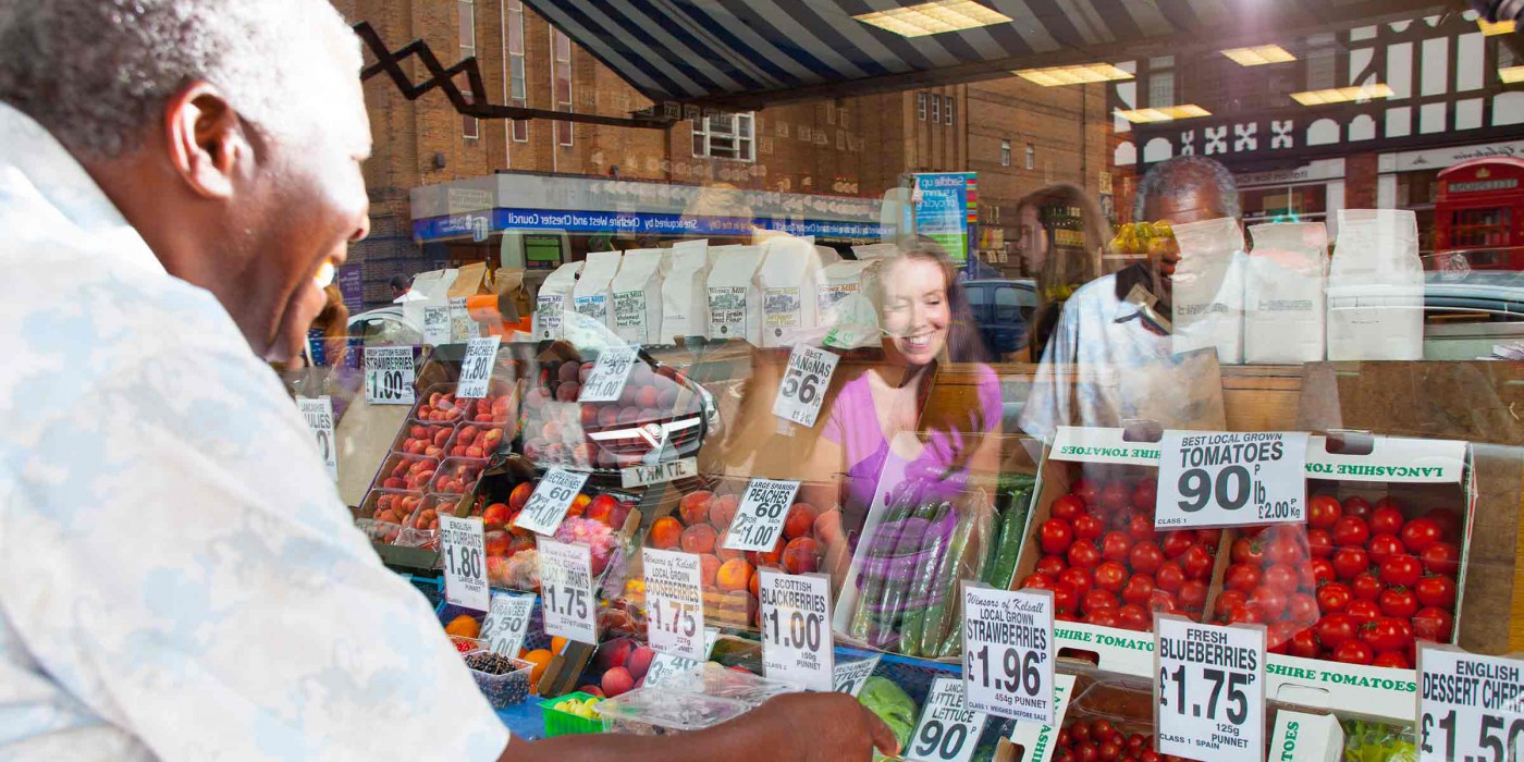 Two people looking in the window of a fruit and veg shop