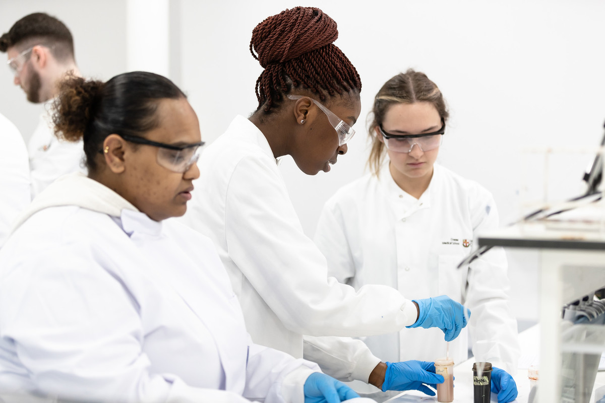 A group of female biomedical science students working together on practical skills training, in large laboratory.