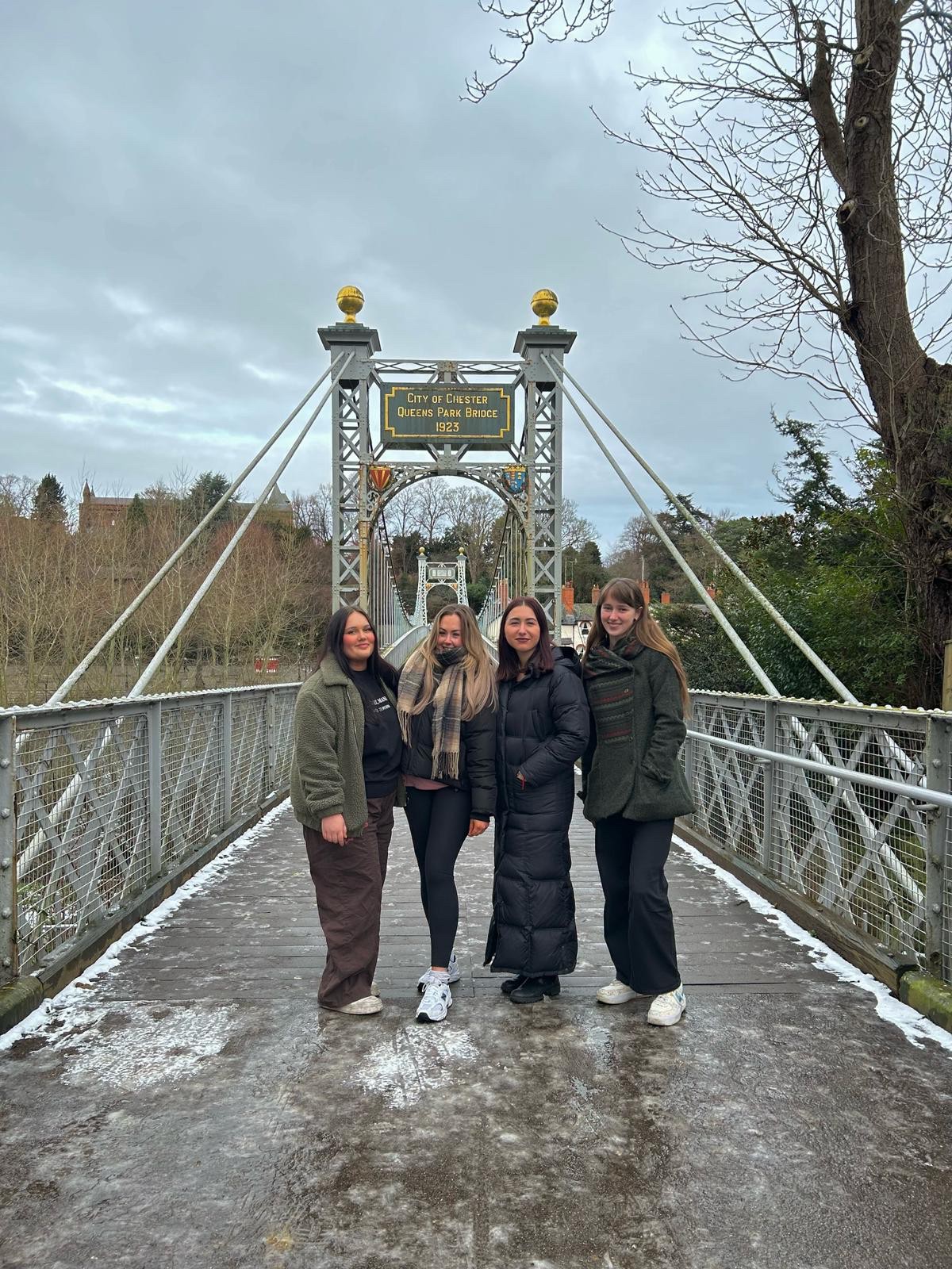 Four female students standing on the Queen's park bridge