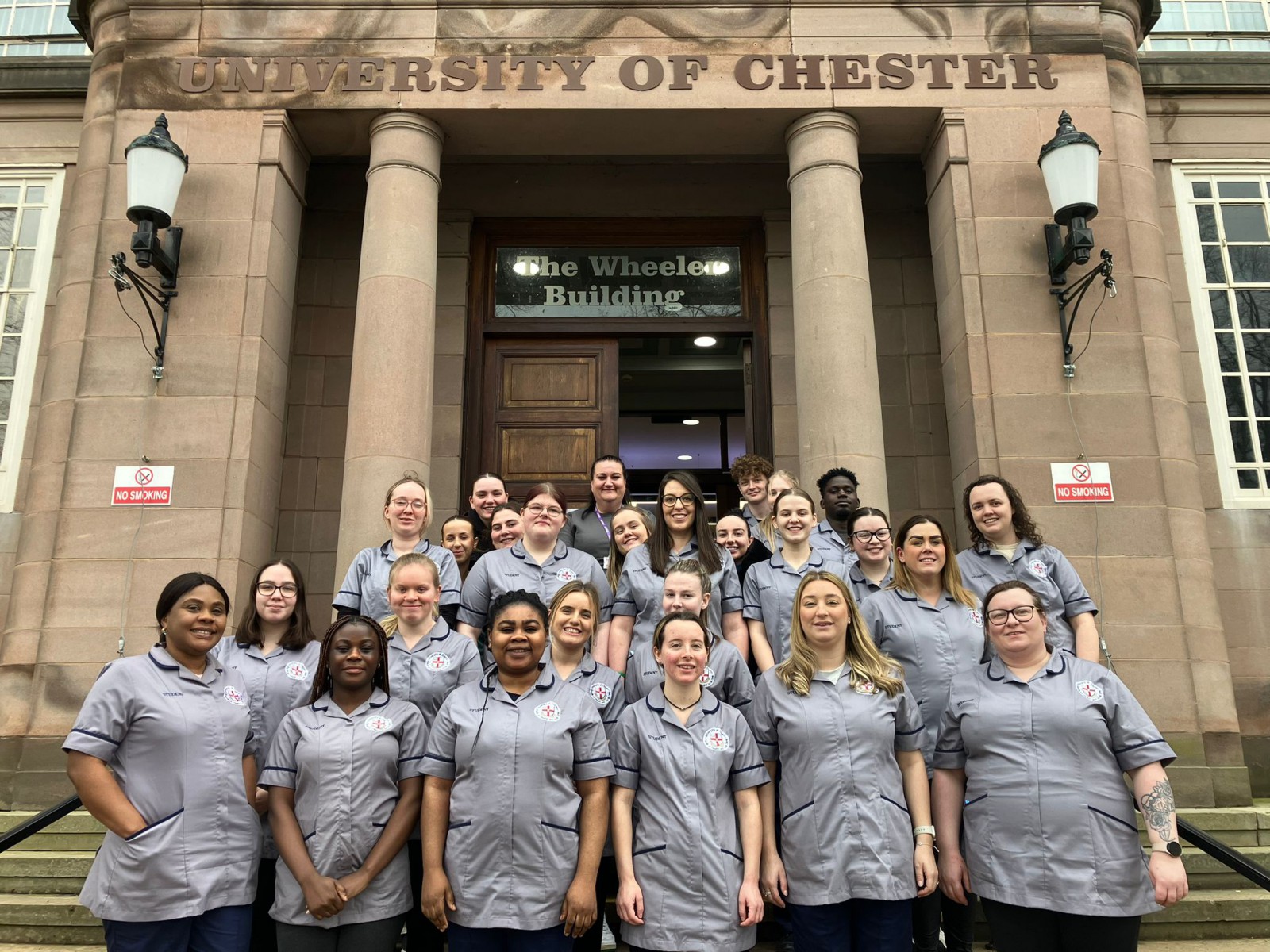 Student Nurse Choir standing facing the camera, smiling. Standing on steps at the entrance of Wheeler Building.