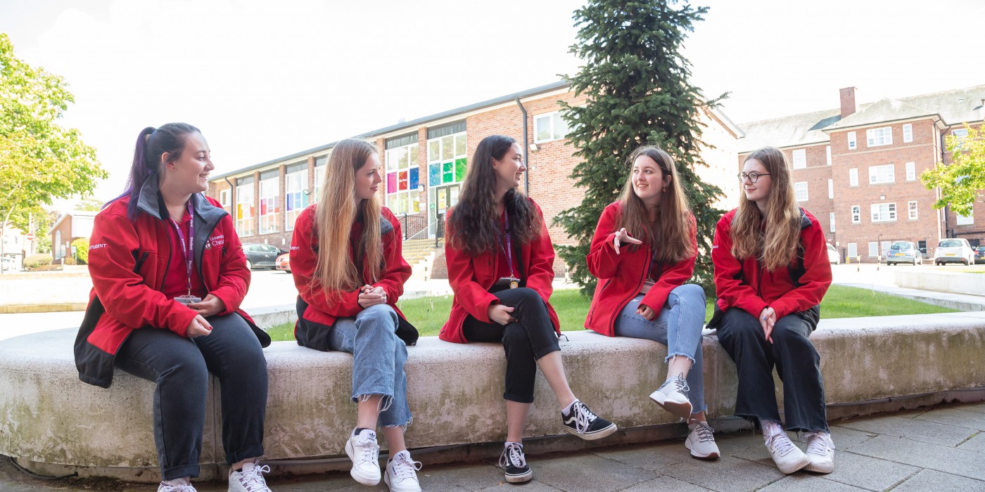Five female students sat on a wall chatting