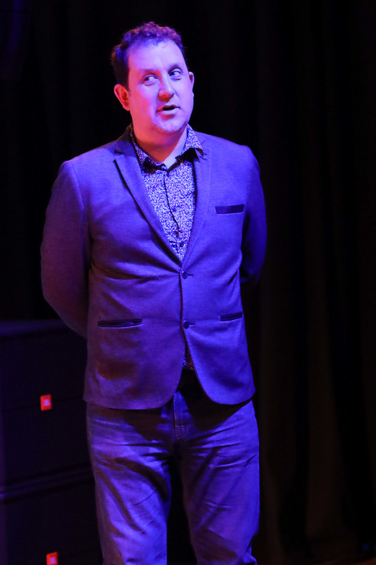 a man wearing a suit standing under stage lighting