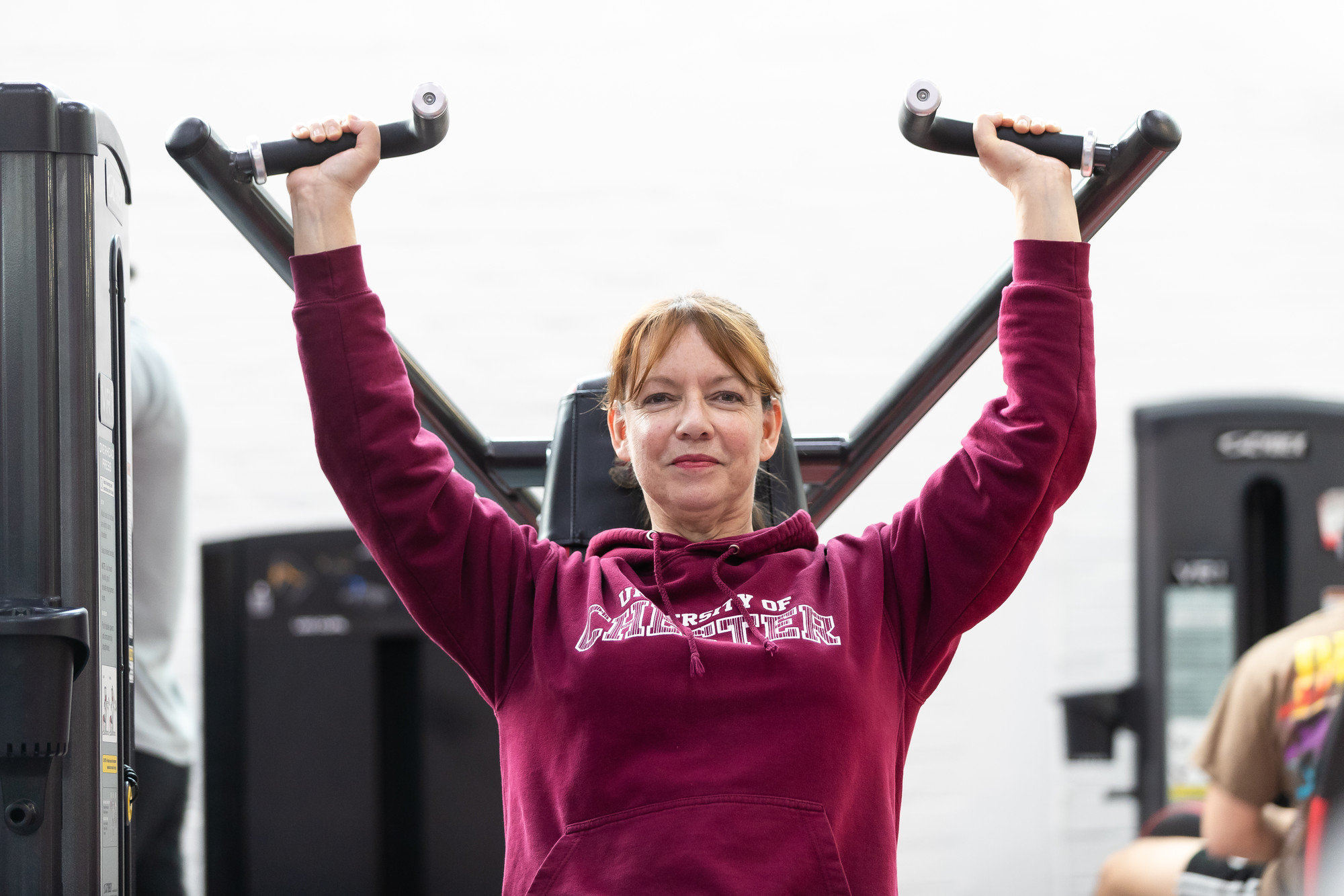 woman on a shoulder press machine at a gym