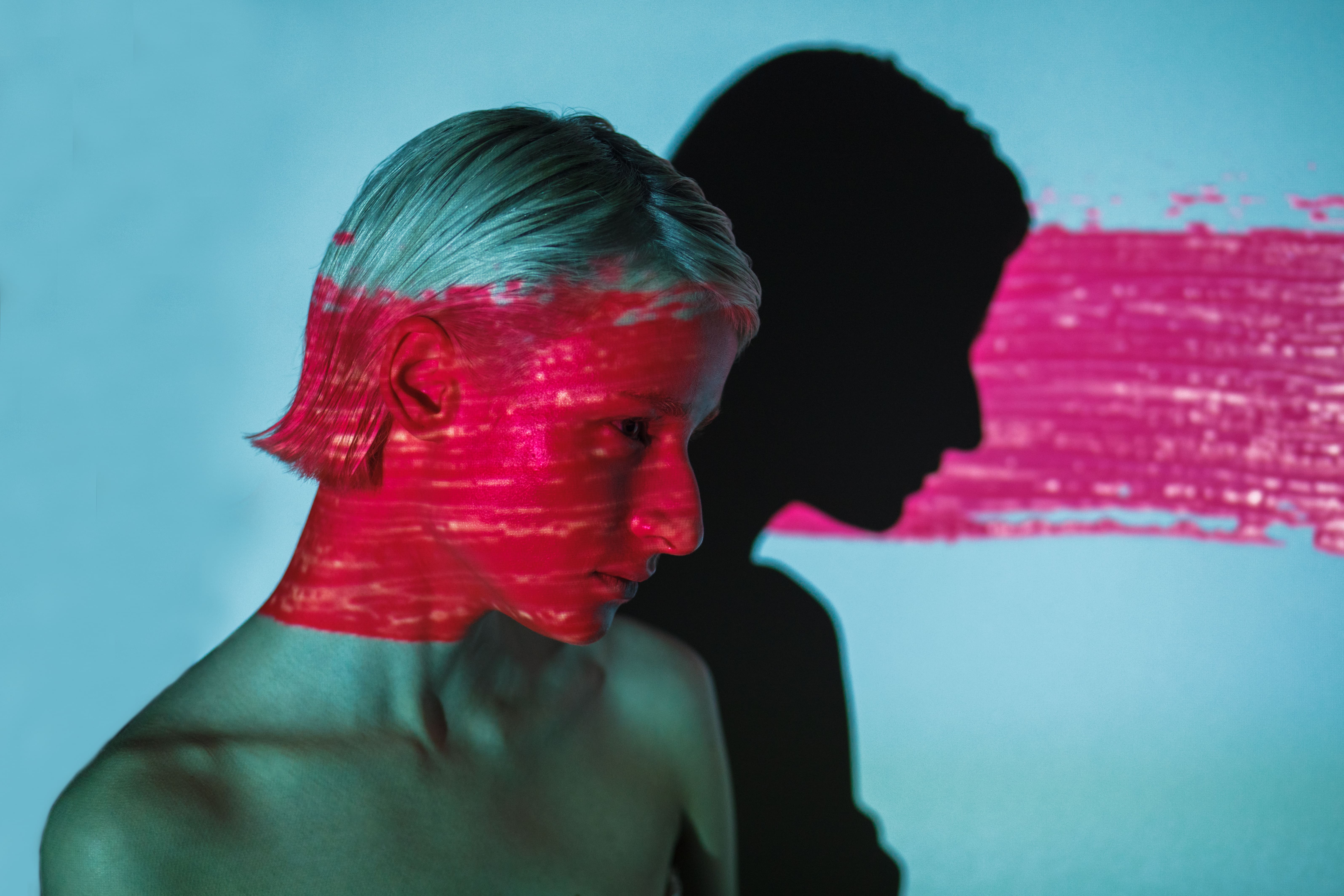 androgyne woman with projection of neon pink stripe on face