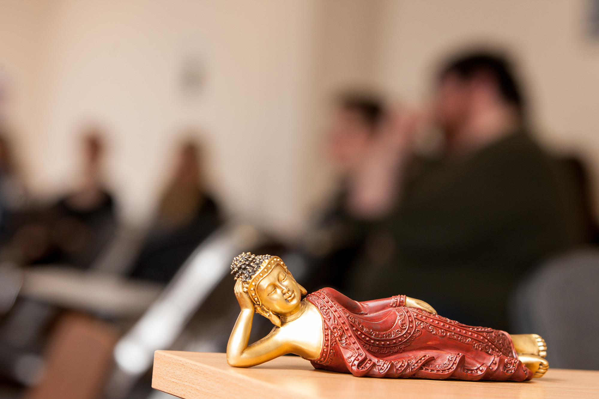Buddah statue on a desk with students blurred in the background
