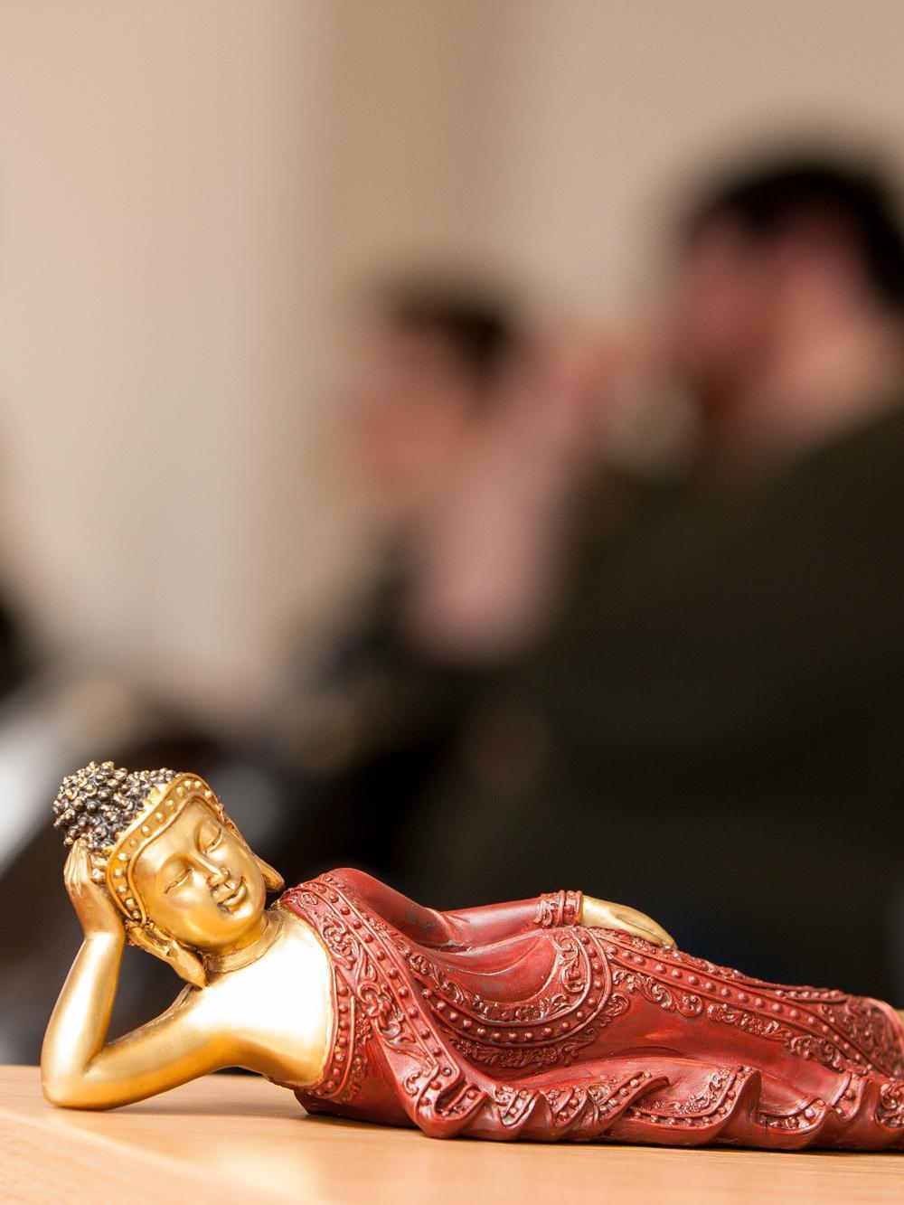 Buddah statue on desk with students blurred in the background