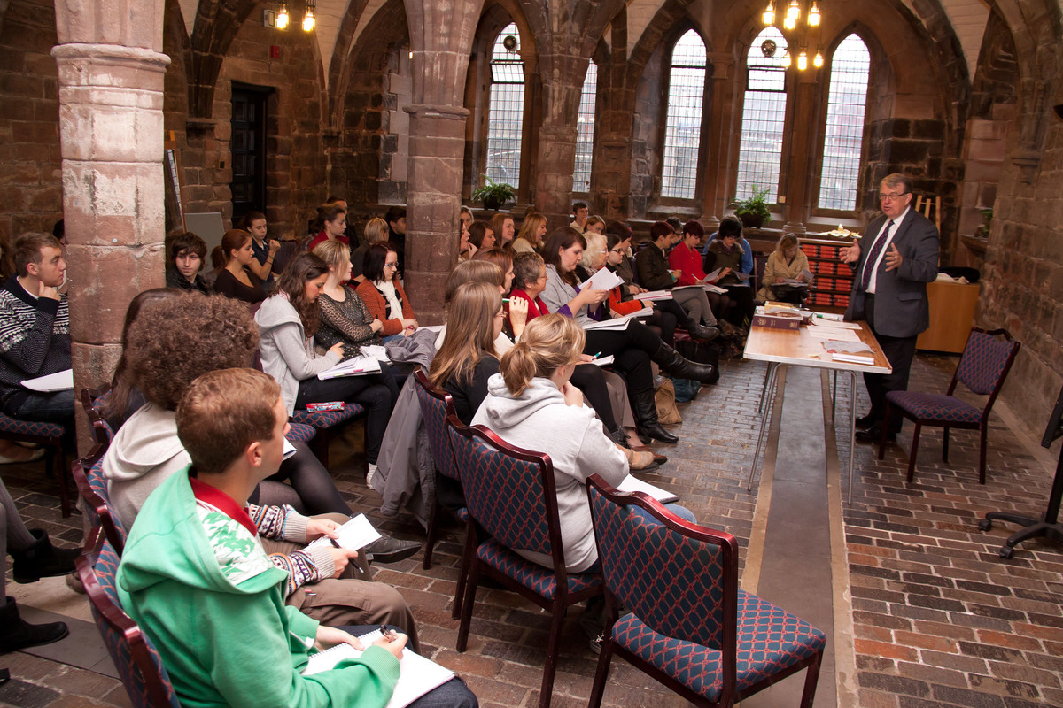 A group of students with a male speaker in a teaching space inside a church.